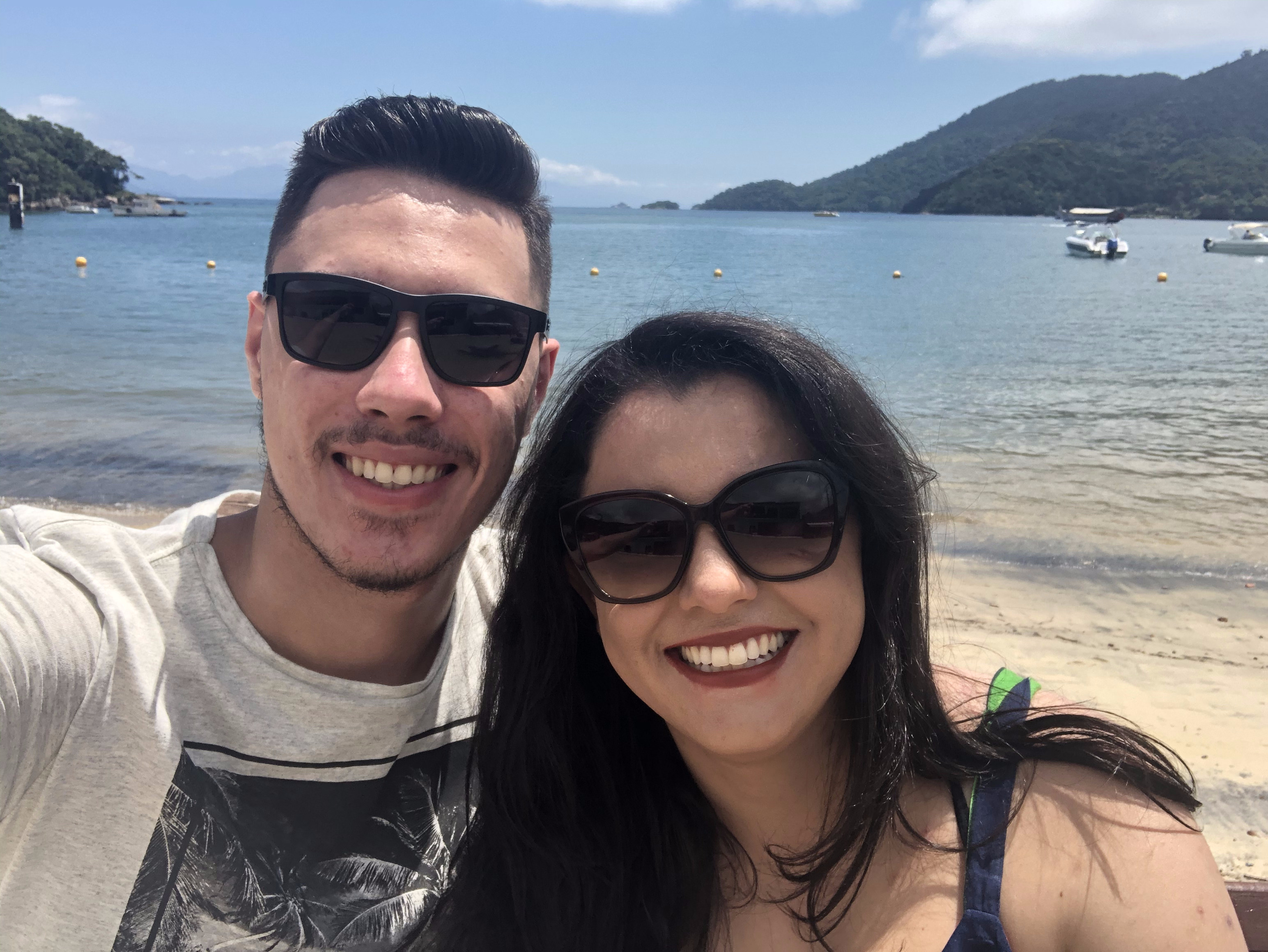 Casal sorrindo de costas para orla da praia