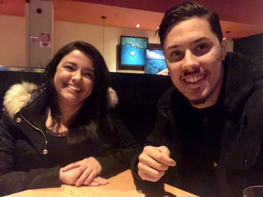 Casal sorrindo de costas para orla da praia