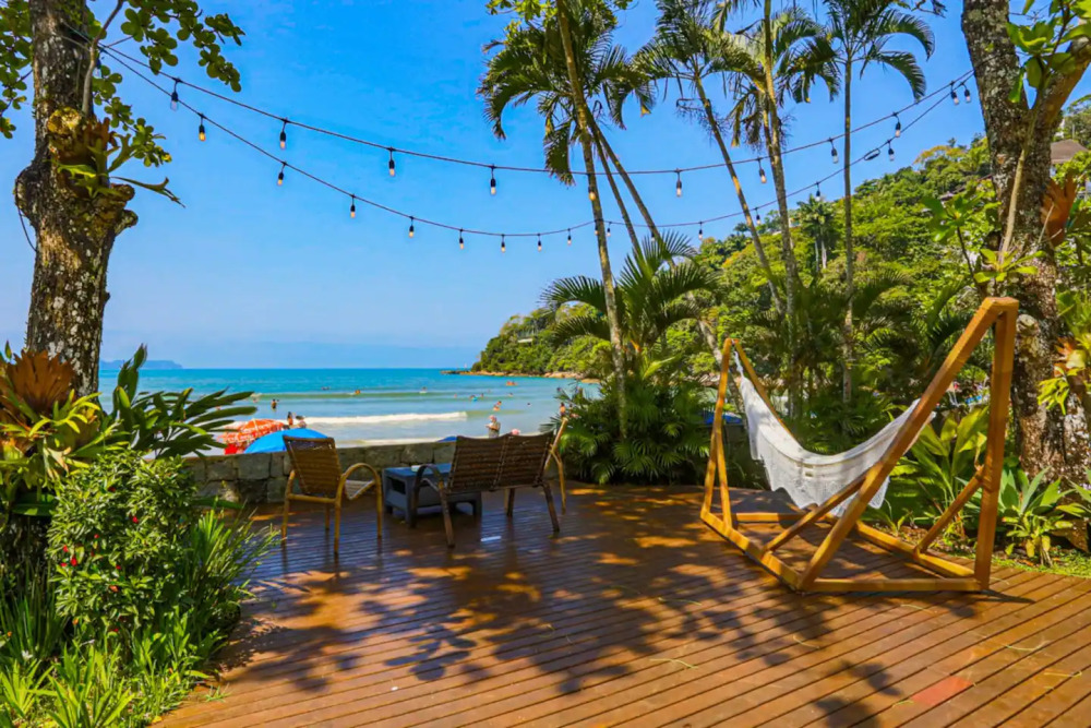 Deck de frente para praia com cadeiras, mesa e rede